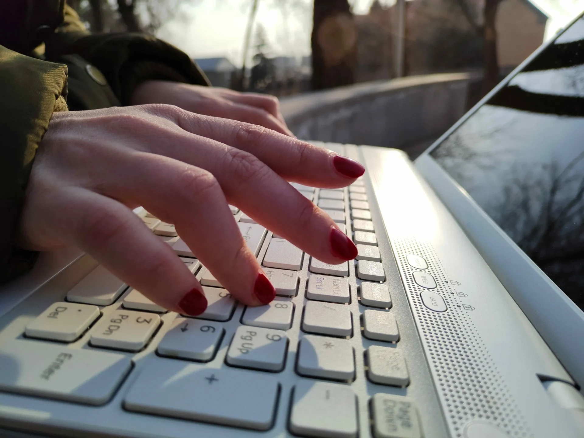 Hands with red nails typing on laptop